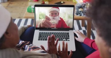 Afrika kökenli Amerikalı anne ve kız Noel 'de ekranda Noel Baba' nın görüntülü araması için laptop kullanıyorlar. Noel, şenlik ve iletişim teknolojisi.