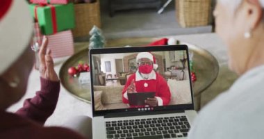 Birçok kıdemli bayan arkadaş, Noel Baba 'nın ekranda olduğu bir video için dizüstü bilgisayar kullanıyor. Covid 19 salgını sırasında Noel, şenlik ve iletişim teknolojisi.