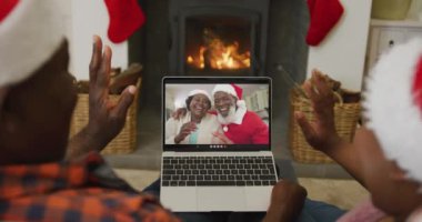 Noel Baba şapkalı Afro-Amerikan çift, dizüstü bilgisayarlarını ekranda çift olarak Noel 'de görüntülü konuşma için kullanıyorlar. Noel, şenlik ve iletişim teknolojisi.
