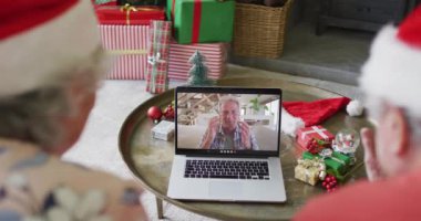 Üst düzey Kafkasyalı çift ekranda mutlu bir adamla yılbaşı görüntüsü için dizüstü bilgisayar kullanıyor. Noel, şenlik ve iletişim teknolojisi.