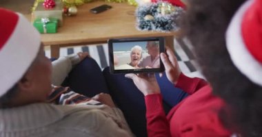 Afrika kökenli Amerikalı anne ve kız. Yılbaşı videoları için ekranda bir çiftle tablet kullanıyorlar. Noel, şenlik ve iletişim teknolojisi.