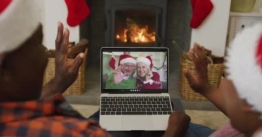 Noel Baba şapkalı Afro-Amerikan çift, dizüstü bilgisayarlarını ekranda çift olarak Noel 'de görüntülü konuşma için kullanıyorlar. Noel, şenlik ve iletişim teknolojisi.