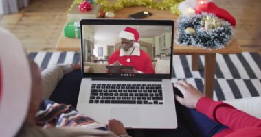 Afrika kökenli Amerikalı anne ve kız Noel 'de ekranda Noel Baba' nın görüntülü araması için laptop kullanıyorlar. Noel, şenlik ve iletişim teknolojisi.