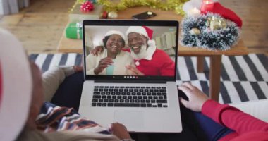 Afrika kökenli Amerikalı anne ve kız. Ekrandaki çiftle yılbaşı videosu için dizüstü bilgisayar kullanıyorlar. Noel, şenlik ve iletişim teknolojisi.