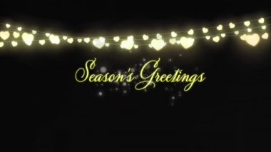 Mevsimin tebrik mesajlarının animasyonu ve siyah arka planda noel perisi ışıkları süslemesi. Yeni yıl, Noel, gelenek ve dijital olarak üretilen kutlama konsepti.