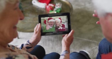 Üst düzey Kafkasyalı çift, mutlu çiftle Noel görüntülü konuşma yapmak için tablet kullanıyor. Noel, şenlik ve iletişim teknolojisi.