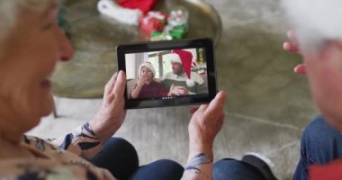 Üst düzey Kafkasyalı çift, mutlu bir aileyle Noel videosu için tablet kullanıyor. Noel, şenlik ve iletişim teknolojisi.