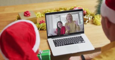 Noel Baba şapkalı beyaz bir baba ve oğul, Noel 'de aileleriyle birlikte ekranda görüntülü konuşma tableti kullanıyorlar. Noel, şenlik ve iletişim teknolojisi.