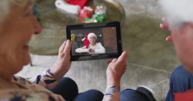 Son sınıf Kafkas çifti gülümsüyor ve ekranda bir kadınla noel videosu için tablet kullanıyorlar. Noel, şenlik ve iletişim teknolojisi.