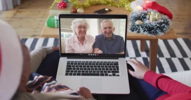 Afrika kökenli Amerikalı anne ve kız. Ekrandaki çiftle yılbaşı videosu için dizüstü bilgisayar kullanıyorlar. Noel, şenlik ve iletişim teknolojisi.