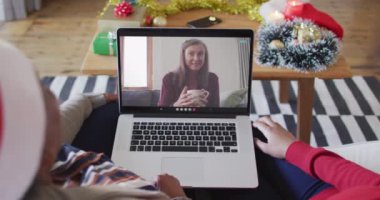 Afrika kökenli Amerikalı anne ve kız. Ekrandaki kadınla yılbaşı videosu için dizüstü bilgisayar kullanıyorlar. Noel, şenlik ve iletişim teknolojisi.