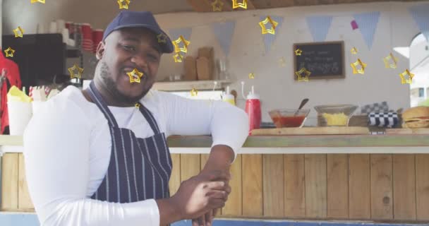 カウンターにもたれて幸せなアフリカ系アメリカ人男性フードベンダーの上に金の星のアニメーション 中小企業 テイクアウト食品 成功と幸福のライフスタイルのコンセプトデジタルで生成されたビデオ — ストック動画
