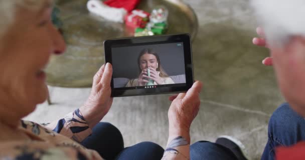 Ein älteres kaukasisches Paar nutzt ein Tablet für ein Weihnachts-Videotelefonat mit einer glücklichen Frau auf dem Bildschirm. Weihnachten, Fest und Kommunikationstechnologie.