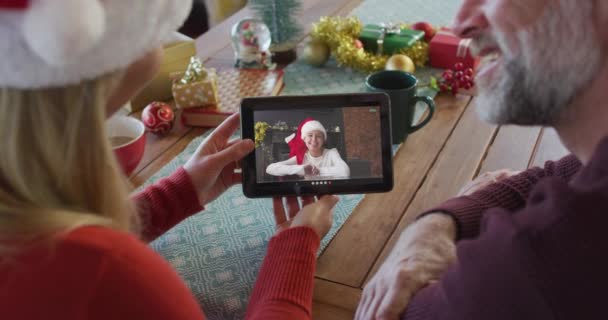 画面上の女性とクリスマスのビデオ通話のためのタブレットを使用してサンタの帽子と白人のカップル クリスマスやお祭りや通信技術は — ストック動画
