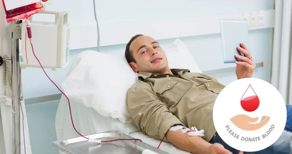病院の献血中にベッドの上にデジタルタブレットで寝そべって笑顔の男性ドナーの肖像画 医療と意識のデジタル複合体は — ストック写真