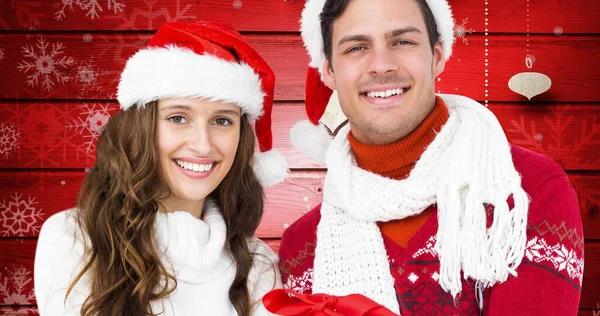 赤い背景にサンタの帽子と暖かい服を着て幸せな若いカップルの肖像画 クリスマスのお祭り伝統と冬の休日 — ストック写真
