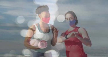 Yoga minderleri ve plajda yüz maskeleri olan çeşitli bayan arkadaşların üzerinde ışık lekeleri. Dijital olarak üretilen pandemik konsept sırasında sağlık ve fitness.