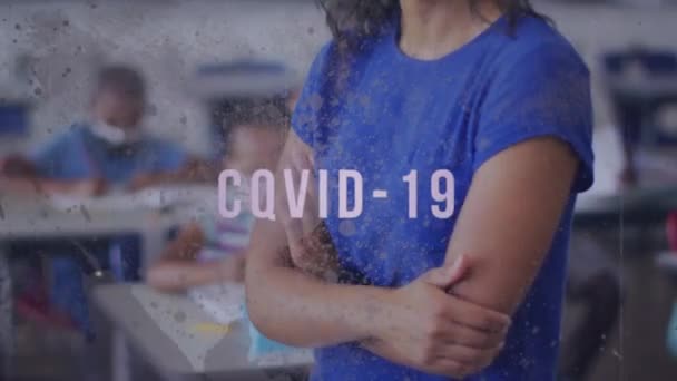 教室のフェイスマスクで女性教師の上にCovid 19テキストのアニメーション グローバルCovid 19パンデミック教育概念デジタルで生成されたビデオ — ストック動画