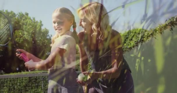 屋外でテニスをする白人の母親と娘の上に草のアニメーション 世界中のスポーツ健康的で活動的なライフスタイルの概念をデジタルで生成し — ストック動画