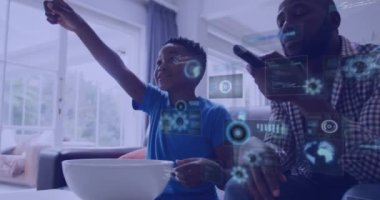 Oğlu televizyon izlerken gülümseyen Afro-Amerikan babası üzerine dijital ekranların animasyonu. küresel bağlantılar ve dijital arayüz konsepti dijital olarak oluşturulmuş video.