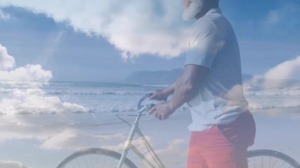 动画的资深非洲裔美国人骑自行车走在沙滩上的云彩 休闲和福利概念数码视频 — 图库视频影像