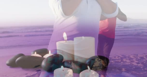 非洲裔美国老人夫妇在海滩上用蜡烛练习瑜伽的动画 休闲和福利概念数码视频 — 图库视频影像
