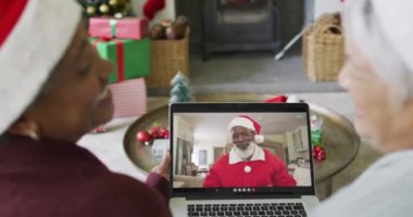 Farklı son sınıf kız arkadaşları Noel 'de ekranda mutlu noel baba videosu için dizüstü bilgisayar kullanıyor. Noel, şenlik ve iletişim teknolojisi.