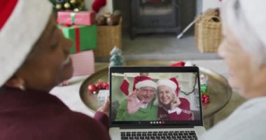 Farklı üst düzey bayan arkadaşlar, mutlu çiftle birlikte ekranda Noel görüntülü konuşma yapmak için dizüstü bilgisayar kullanıyorlar. Noel, şenlik ve iletişim teknolojisi.