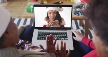 Afrika kökenli Amerikalı anne ve kız. Ekrandaki kadınla yılbaşı videosu için dizüstü bilgisayar kullanıyorlar. Noel, şenlik ve iletişim teknolojisi.