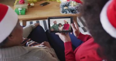 Afrika kökenli Amerikalı anne ve kız. Ekranda aileleriyle birlikte yılbaşı videosu için tablet kullanıyorlar. Noel, şenlik ve iletişim teknolojisi.