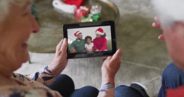 Üst düzey Kafkasyalı çift, mutlu bir aileyle Noel videosu için tablet kullanıyor. Noel, şenlik ve iletişim teknolojisi.