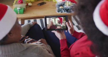 Afrika kökenli Amerikalı anne ve kız. Ekranda aileleriyle birlikte yılbaşı videosu için tablet kullanıyorlar. Noel, şenlik ve iletişim teknolojisi.