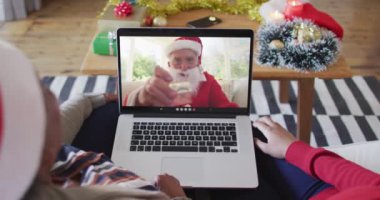 Afrika kökenli Amerikalı anne ve kız Noel 'de ekranda Noel Baba' nın görüntülü araması için laptop kullanıyorlar. Noel, şenlik ve iletişim teknolojisi.