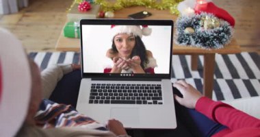 Afrika kökenli Amerikalı anne ve kız. Ekrandaki kadınla yılbaşı videosu için dizüstü bilgisayar kullanıyorlar. Noel, şenlik ve iletişim teknolojisi.