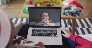 Afrika kökenli Amerikalı anne ve kız. Ekrandaki kadınla yılbaşı videosu için dizüstü bilgisayar kullanıyorlar. Noel, şenlik ve iletişim teknolojisi.