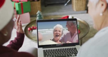 Farklı üst düzey bayan arkadaşlar, mutlu çiftle birlikte ekranda Noel görüntülü konuşma yapmak için dizüstü bilgisayar kullanıyorlar. Noel, şenlik ve iletişim teknolojisi.