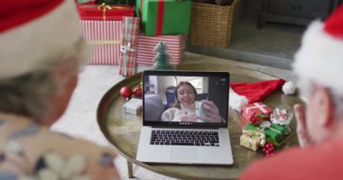 Üst düzey Kafkasyalı çift ekranda mutlu bir kadınla yılbaşı görüntüsü için dizüstü bilgisayar kullanıyor. Noel, şenlik ve iletişim teknolojisi.