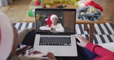 Afrika kökenli Amerikalı anne ve kız. Ekrandaki kadınla yılbaşı videosu için dizüstü bilgisayar kullanıyorlar. Noel, şenlik ve iletişim teknolojisi.