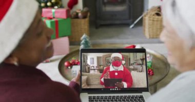 Birçok kıdemli bayan arkadaş, Noel Baba 'nın ekranda olduğu bir video için dizüstü bilgisayar kullanıyor. Covid 19 salgını sırasında Noel, şenlik ve iletişim teknolojisi.
