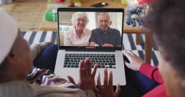 Afrika kökenli Amerikalı anne ve kız. Ekrandaki çiftle yılbaşı videosu için dizüstü bilgisayar kullanıyorlar. Noel, şenlik ve iletişim teknolojisi.