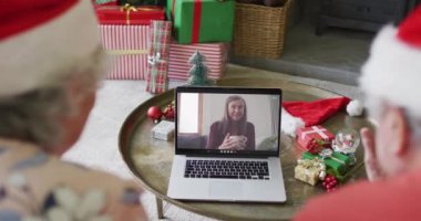 Üst düzey Kafkasyalı çift ekranda mutlu bir kadınla yılbaşı görüntüsü için dizüstü bilgisayar kullanıyor. Noel, şenlik ve iletişim teknolojisi.