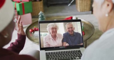 Farklı üst düzey bayan arkadaşlar, mutlu çiftle birlikte ekranda Noel görüntülü konuşma yapmak için dizüstü bilgisayar kullanıyorlar. Noel, şenlik ve iletişim teknolojisi.