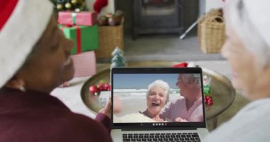 Farklı üst düzey bayan arkadaşlar, mutlu çiftle birlikte ekranda Noel görüntülü konuşma yapmak için dizüstü bilgisayar kullanıyorlar. Noel, şenlik ve iletişim teknolojisi.