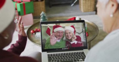 Farklı üst düzey bayan arkadaşlar, mutlu çiftle birlikte ekranda Noel görüntülü konuşma yapmak için dizüstü bilgisayar kullanıyorlar. Noel, şenlik ve iletişim teknolojisi.