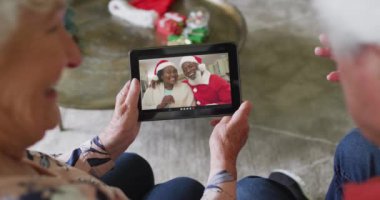 Üst düzey Kafkasyalı çift, mutlu çiftle Noel görüntülü konuşma yapmak için tablet kullanıyor. Noel, şenlik ve iletişim teknolojisi.