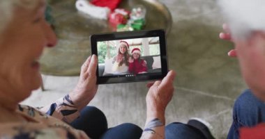 Üst düzey Kafkasyalı çift, mutlu bir aileyle Noel videosu için tablet kullanıyor. Noel, şenlik ve iletişim teknolojisi.