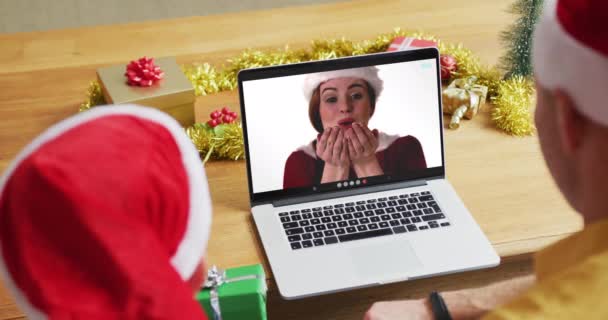 スクリーン上の女性とクリスマスのビデオ通話のためのラップトップを使用してサンタの帽子を持つ白人の父と息子 クリスマスやお祭りや通信技術は — ストック動画