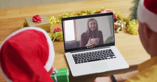 白种人的父亲和儿子戴着桑塔帽 他们用笔记本电脑和屏幕上的女人一起打圣诞视频电话 圣诞节 节日和通信技术 — 图库视频影像
