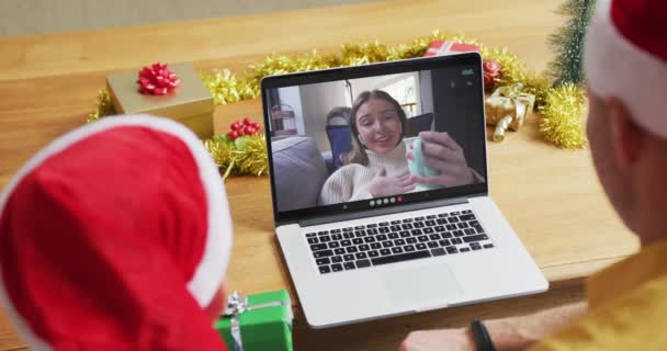 スクリーン上の女性とクリスマスのビデオ通話のためのラップトップを使用してサンタの帽子を持つ白人の父と息子 クリスマスやお祭りや通信技術は — ストック動画