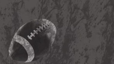 Gri arka planda Amerikan futbol topunun animasyonu. küresel spor ve yarışma konsepti dijital olarak oluşturulmuş video.